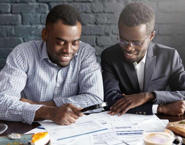 happy-african-american-office-workers-dressed-formal-clothing-having-cheerful-looks-studying-amalyzing-legal-documents-table-using-magnifying-glass-while-getting-papers-ready-meeting